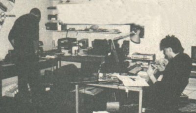 A corner of ZZAP! Editorial. On the left Gary Liddon watching the NEC work, while Gary Penn discusses a serious spelling error with his Apricot.